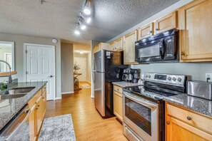 Una cocina moderna con electrodomésticos de acero inoxidable, gabinetes de madera y encimera de granito.