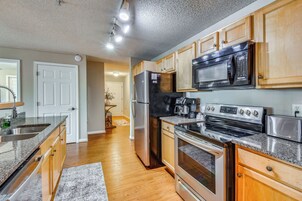 A modern kitchen with stainless steel appliances, wooden cabinets, and a granite countertop.