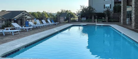 A rectangular swimming pool with a 3-foot depth marker, surrounded by lounge chairs and a stone wall.