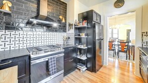 A modern kitchen with a black and white tiled backsplash, stainless steel appliances, and a black refrigerator. - 'the Homecoming Suite' in the Heart of Murray, KY (Murray)