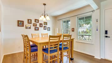 A dining room with a wooden table and chairs, a chandelier, and framed pictures on the wall.