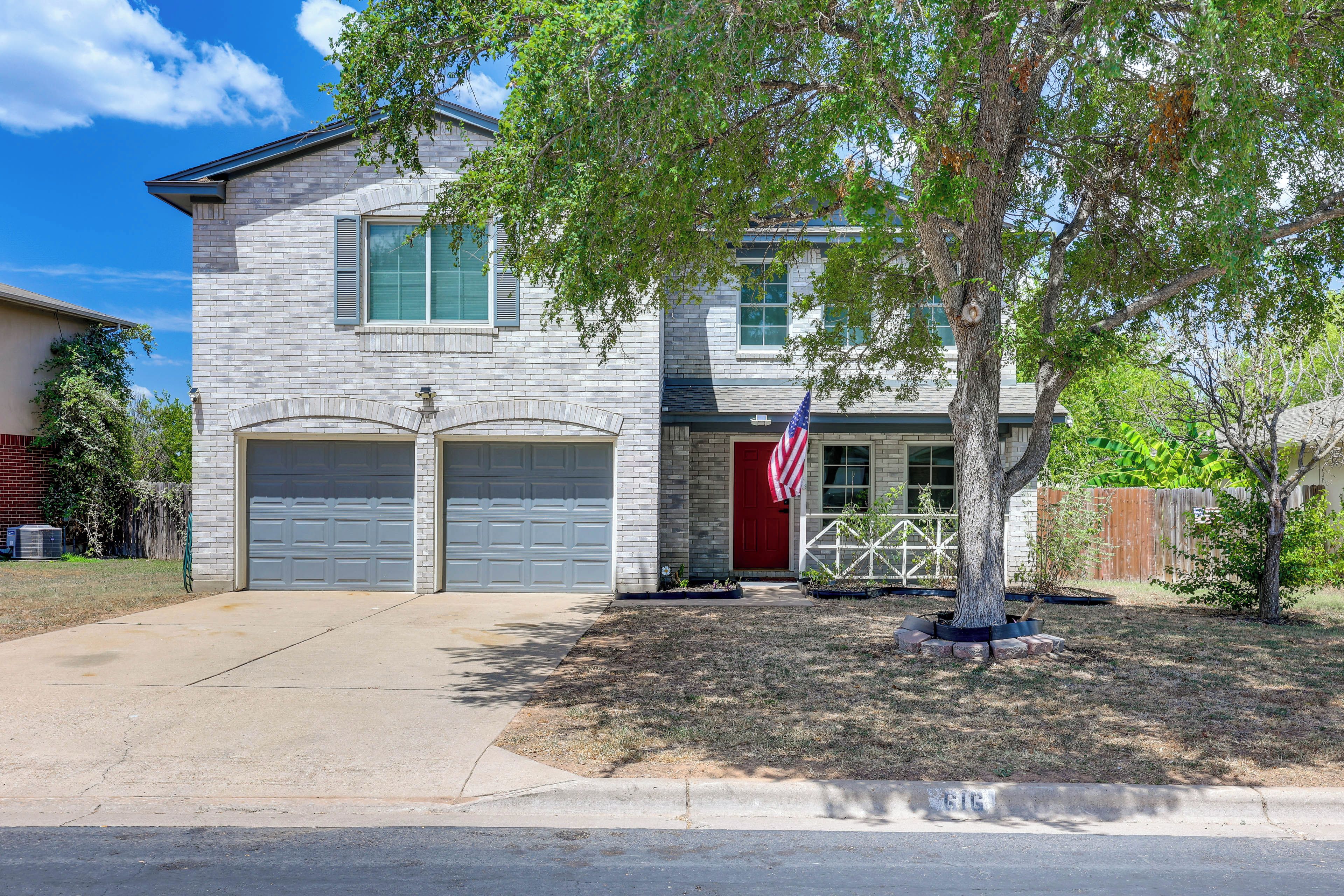 A two-story house with a garage, a red door, and an American flag.