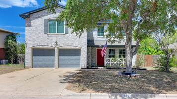 A two-story house with a garage, a red door, and an American flag.