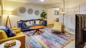 A living room with a sofa, armchairs, a coffee table, a TV, and a ceiling fan. - Remote Work Ready! Walkable Fayetteville Home (Fayetteville)