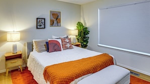 A bedroom with a bed, nightstands, a lamp, a window with blinds, and a plant. - Remote Work Ready! Walkable Fayetteville Home (Fayetteville)