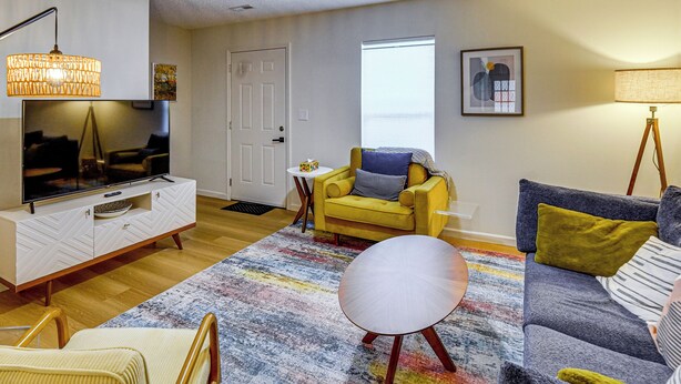 A living room with a television, sofa, armchair, and a colorful rug. - Remote Work Ready! Walkable Fayetteville Home (Fayetteville)