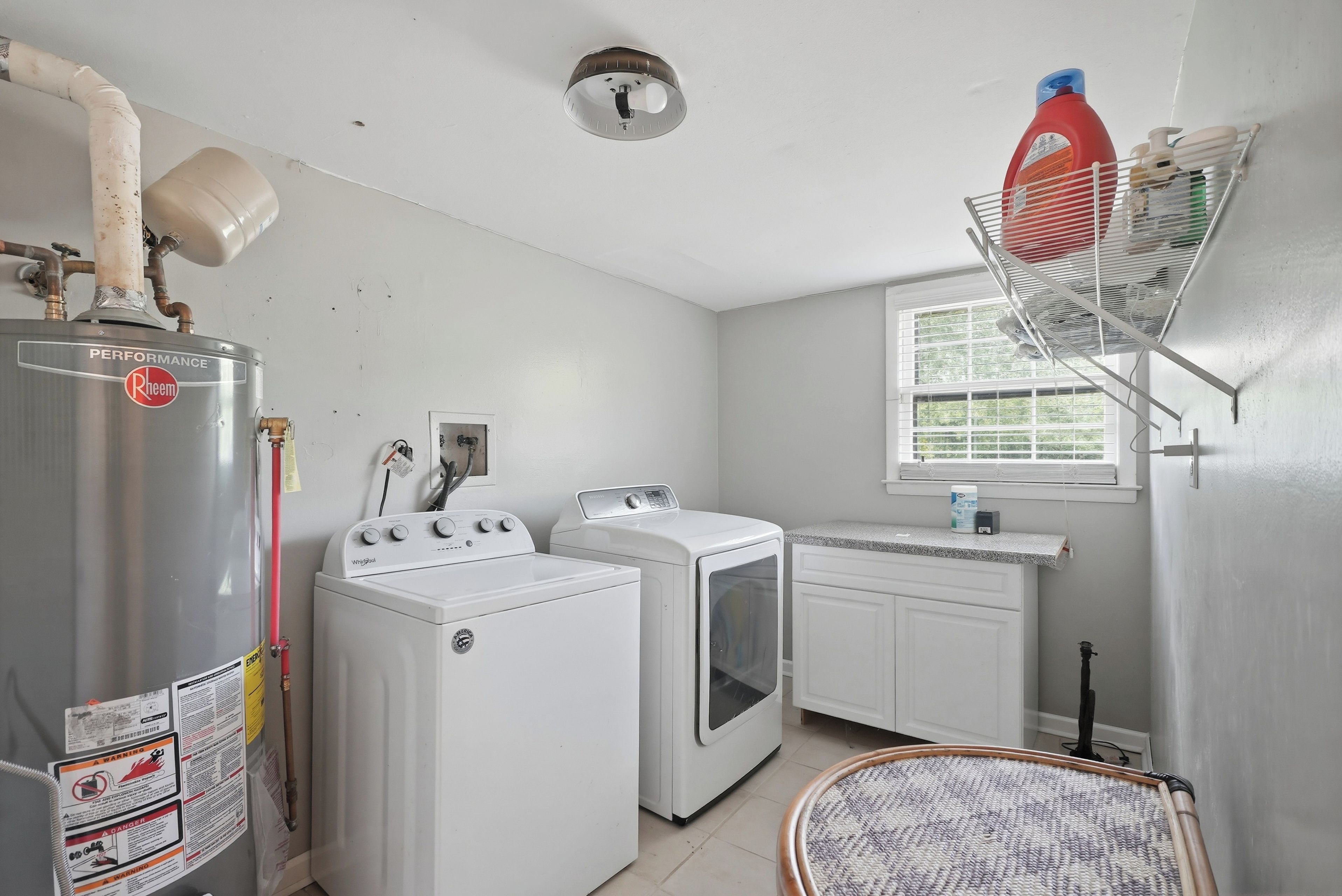 A laundry room with a water heater, washing machines, and a drying rack.