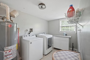 A laundry room with a water heater, washing machines, and a drying rack.
