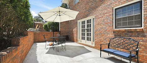 A patio with a table and chairs, a bench, and a large umbrella.