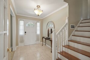 A hallway with a white door, a mirror, a table, and a staircase. - Private Pool, Patio! Spacious Home in Decatur (Decatur)