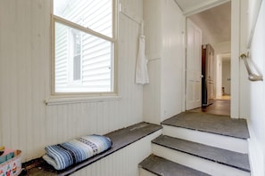 A staircase leading to a door, a window with blinds, and a rolled-up mat on the floor.