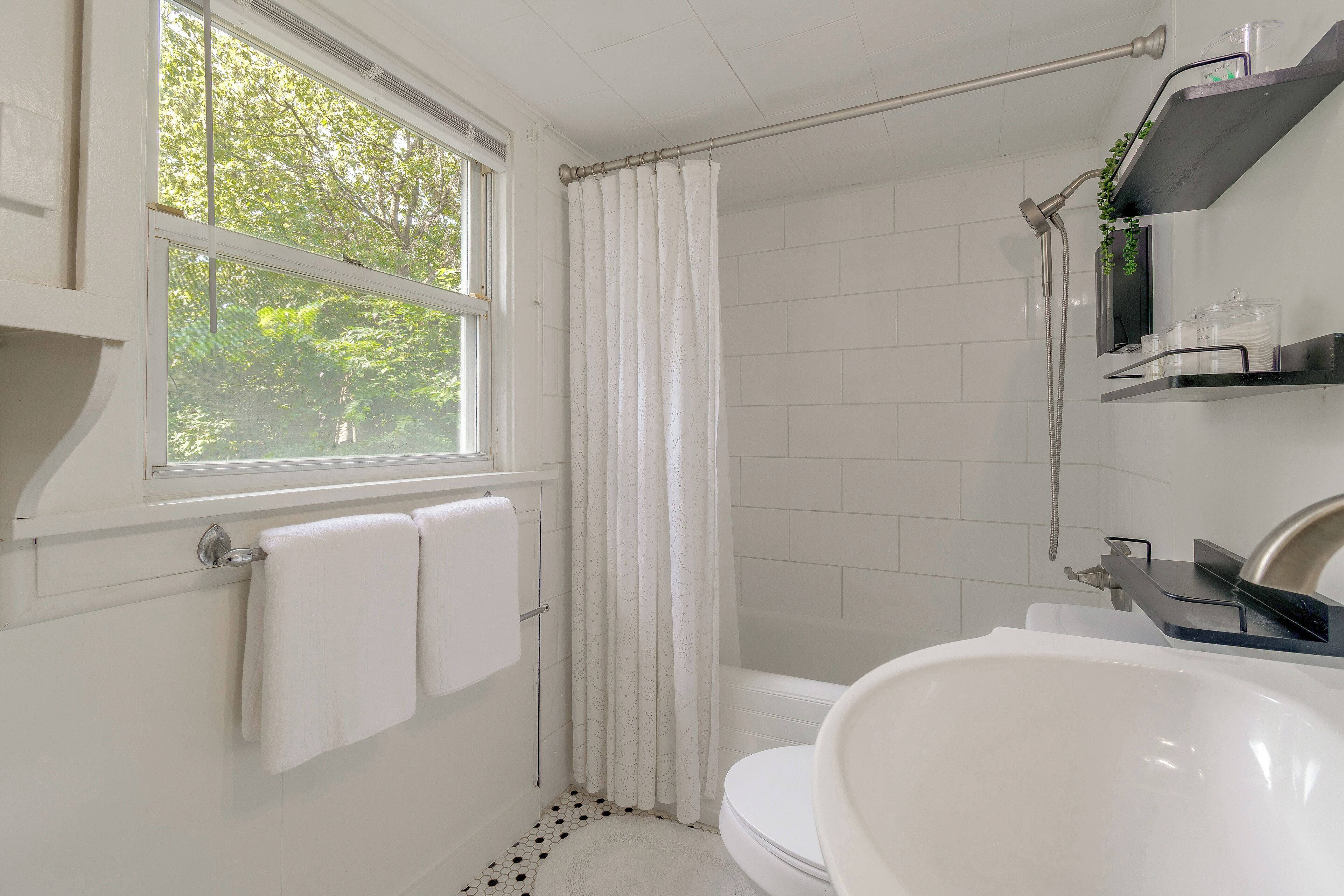 A bathroom with a bathtub, toilet, and a window with a view of trees.