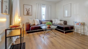 Una sala de estar moderna con un sofá de cuero, una mesa de centro de vidrio y una mesita de noche con una lámpara.