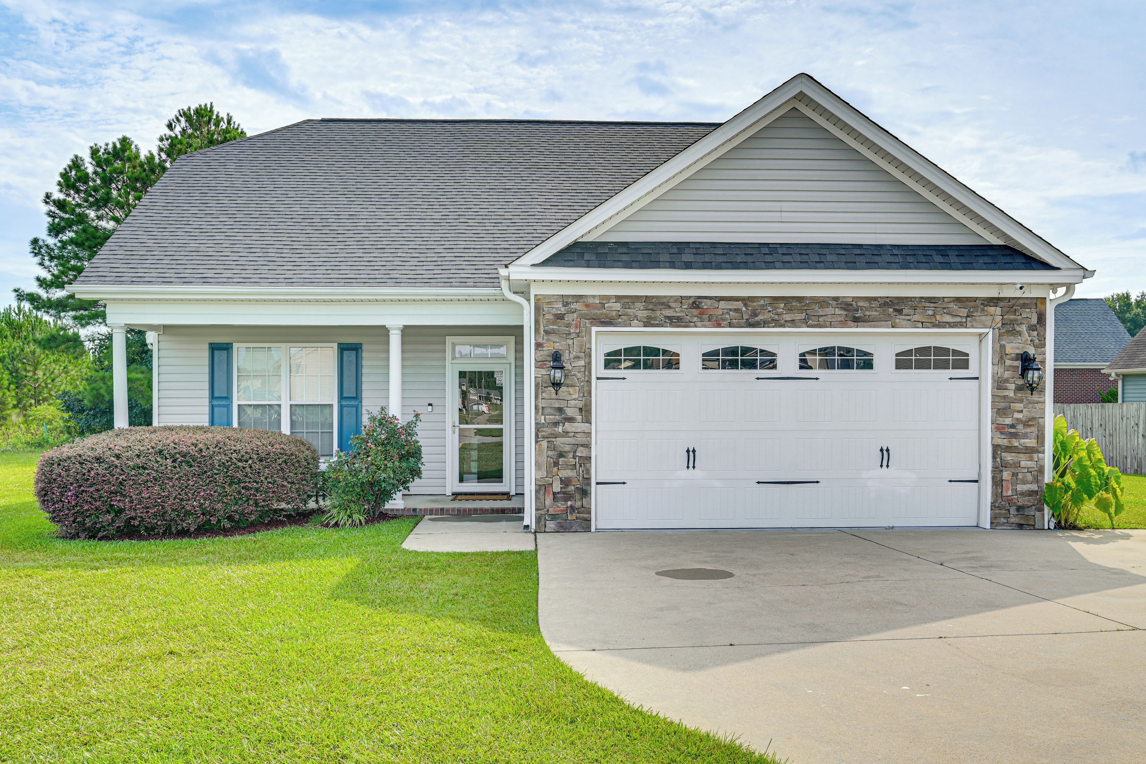 A two-story house with a garage, a stone facade, and a well-maintained lawn.