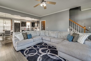 A modern living room with a sectional sofa, a patterned rug, and a ceiling fan. - 3 Mi to Ecu! Modern Home w/ Game Room (Greenville)