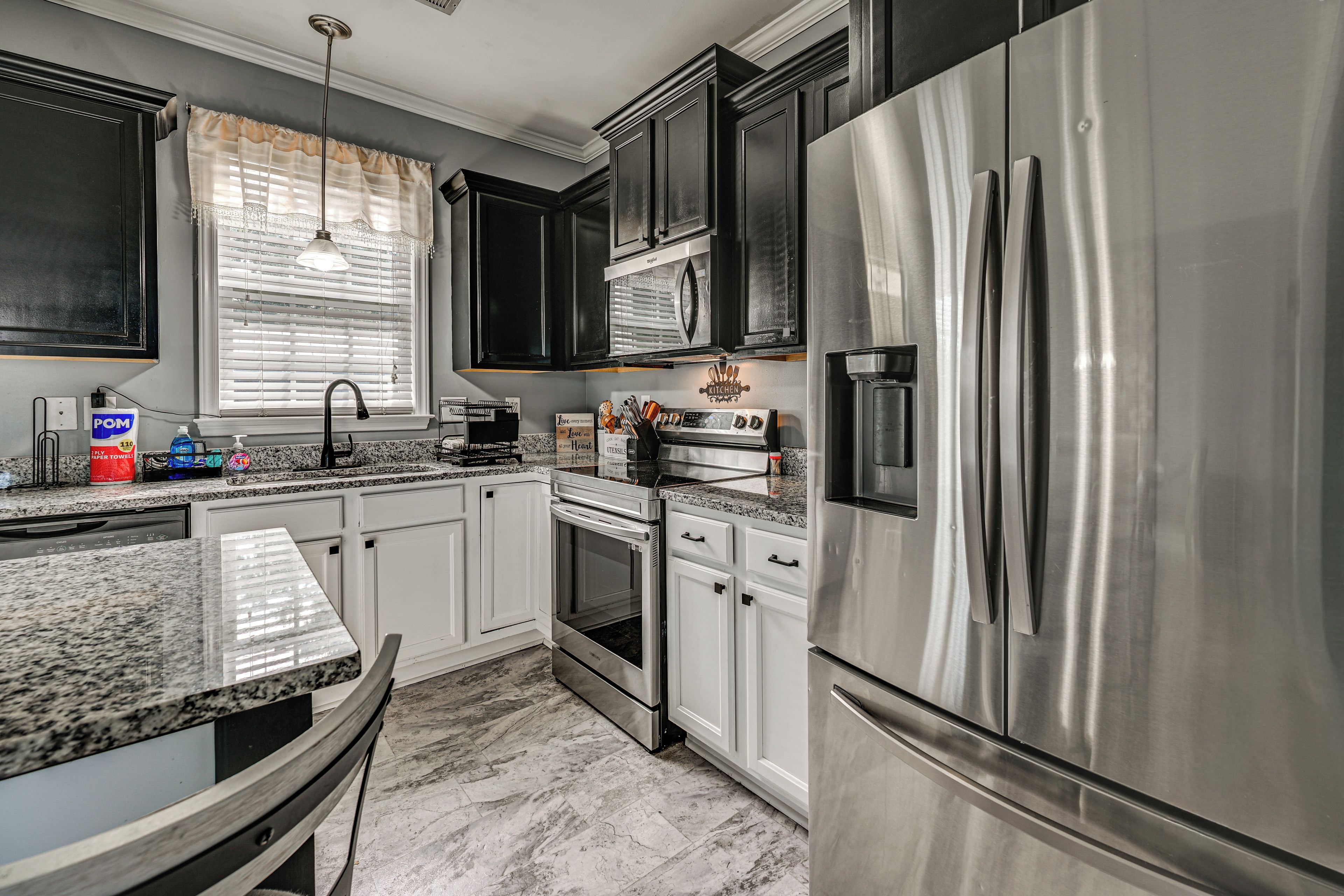 A modern kitchen with stainless steel appliances, white cabinetry, and a granite countertop.