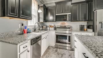 A kitchen with dark cabinets, stainless steel appliances, and a granite countertop.