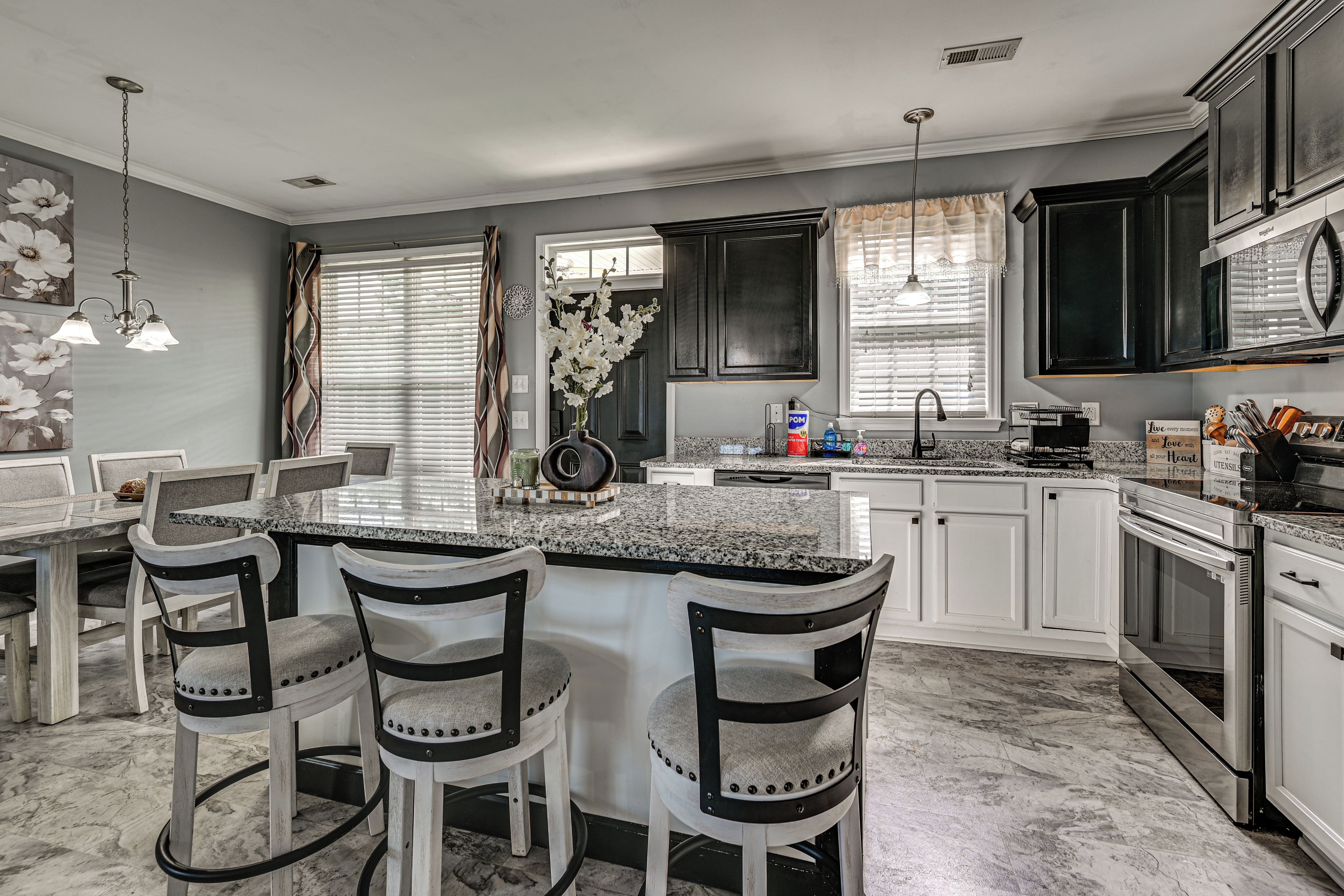 A modern kitchen with a central island, bar stools, a built-in oven, and a stainless steel refrigerator.