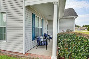 A covered porch with two chairs and a table, a brick base, and a hedge. - 3 Mi to Ecu! Modern Home w/ Game Room (Greenville)