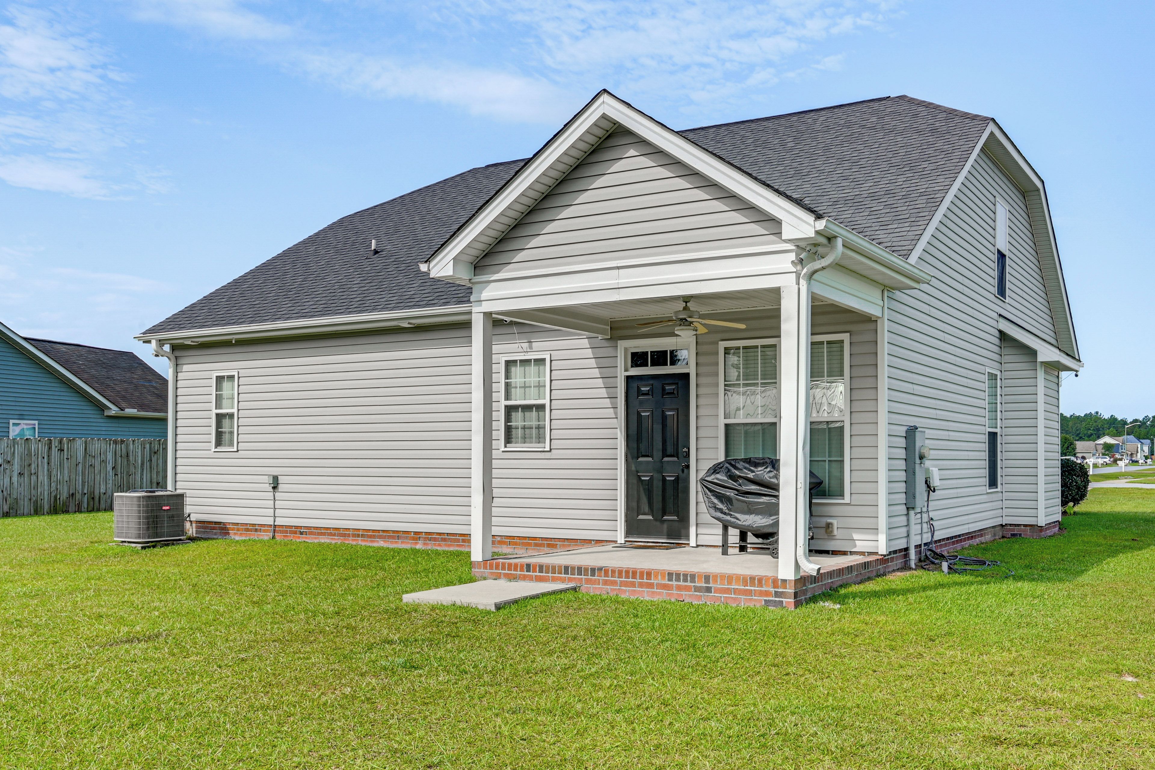 A single-story house with a front porch, a black door, and a small brick foundation.
