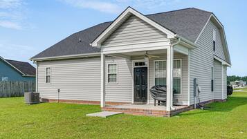 A single-story house with a front porch, a black door, and a small brick foundation.