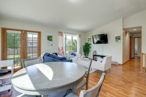 A spacious living area with a round dining table, a sofa, and a TV mounted on the wall. - 5BR Home Close to Moorhead Home & Fargo (Moorhead)