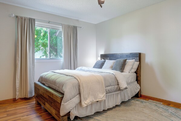 A bedroom with a wooden bed, a window with curtains, and a ceiling light.