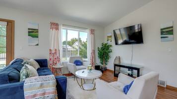 A modern living room with a sofa, armchairs, a coffee table, and a TV mounted on the wall.