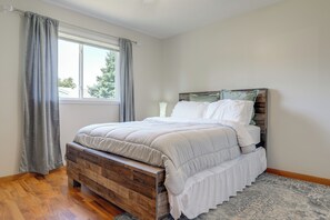 Une chambre à coucher avec un lit en bois, une fenêtre avec des rideaux et un tapis à motifs.