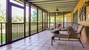 Un portico coperto con una ventola a soffitto, un tavolo da pranzo e mobili in vimini.