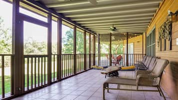 A covered porch with a ceiling fan, a dining table, and wicker furniture.