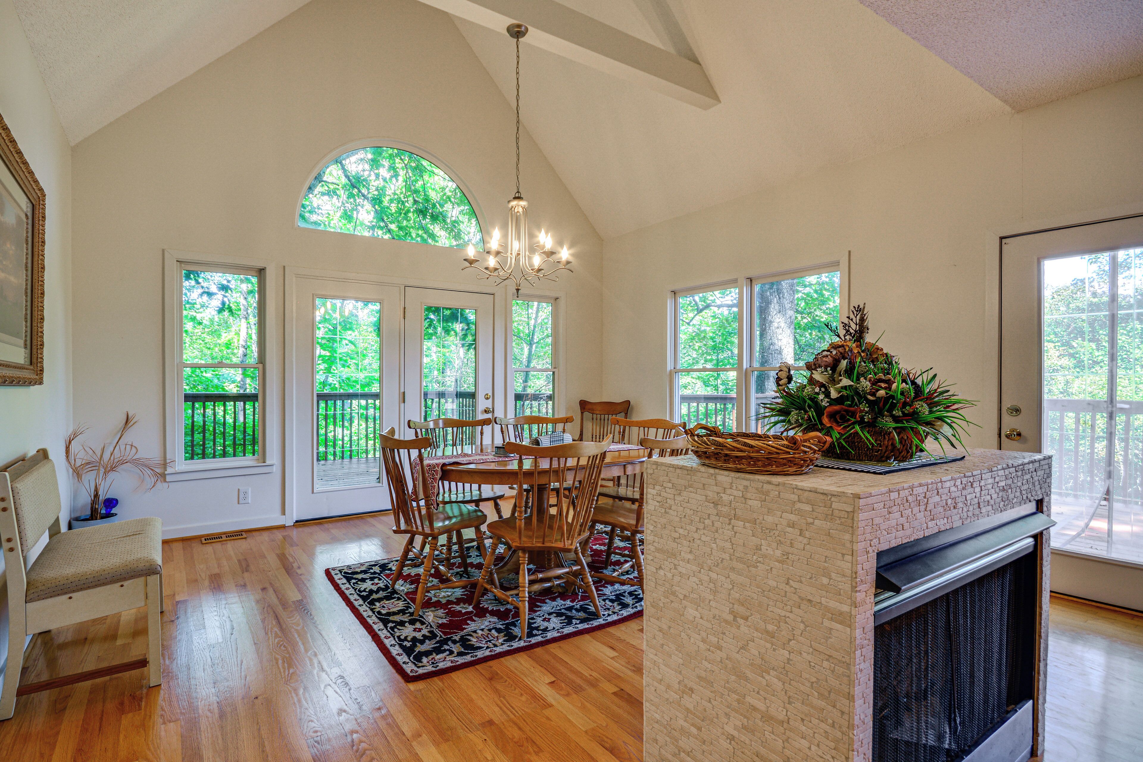 A dining area with a wooden table and chairs, a chandelier, and a fireplace.