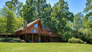 A large wooden cabin with a prominent chimney, large windows, and a covered porch area. - Pinnacle Lakefront Retreat: Dock, Canoe & Fire Pit (Pinnacle)