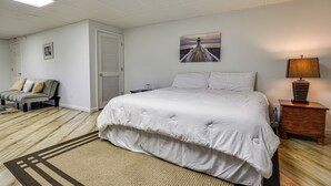A bedroom with a large bed, a nightstand, a lamp, a painting, and a door. - Pinnacle Lakefront Retreat: Dock, Canoe & Fire Pit (Pinnacle)
