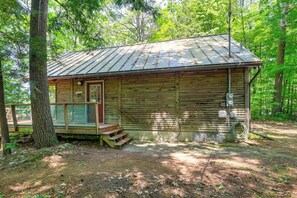 A rustic cabin with a metal roof, wooden walls, and a porch.