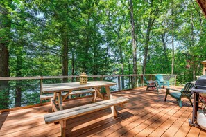 A wooden deck with picnic tables and chairs overlooking a forested area.