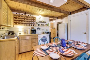 A kitchen with wooden cabinets, a stove, and a dining table set with plates and a pitcher.