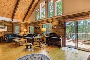 A log cabin interior with a piano, seating area, and large windows. - Lakefront Cabin w/ Views & Dock in Brandon (Brandon)
