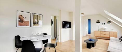 A modern living room with a dining area, a TV, and a sofa.