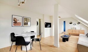 Una sala moderna con comedor, televisor y sofá.