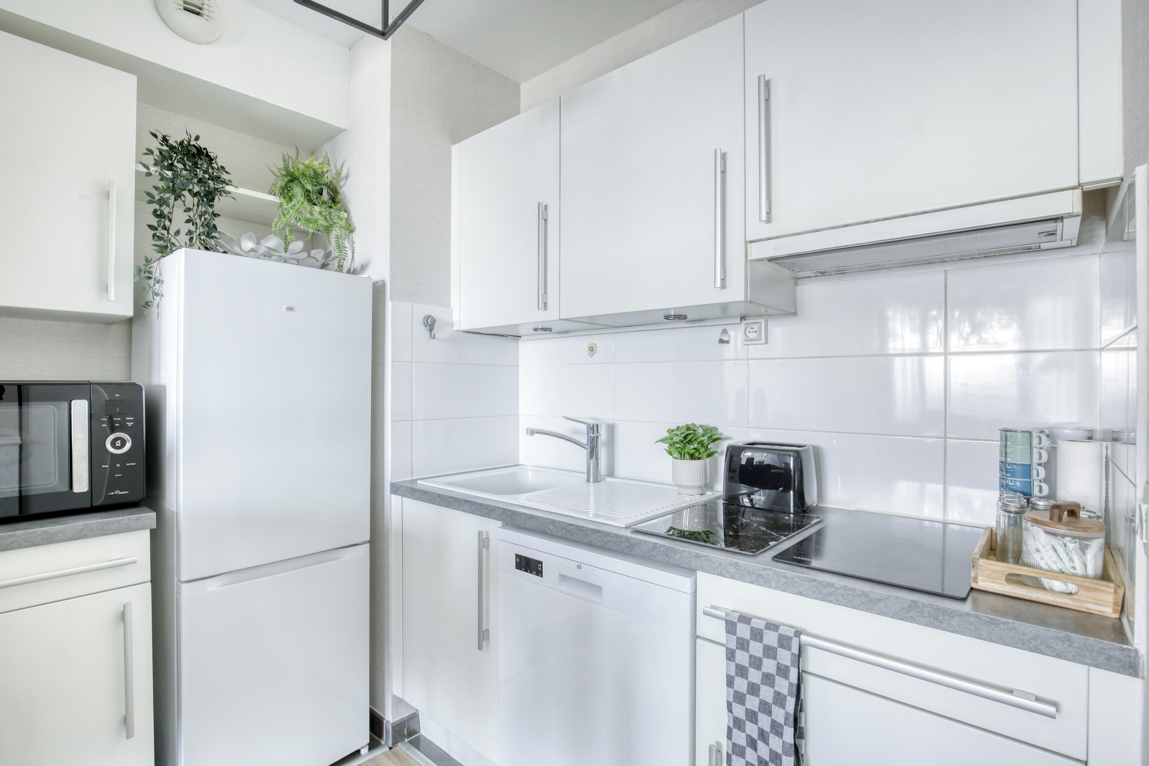 A modern kitchen with white cabinetry, a built-in microwave, a sink, and a toaster.
