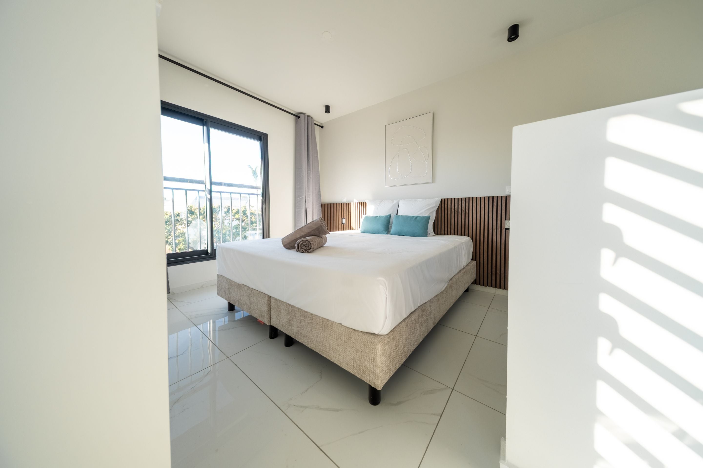 Ein modernes Schlafzimmer mit einem großen Bett, Blick ins Freie und einer Deckenleuchte.