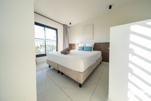 A modern bedroom with a large bed, a view of the outdoors, and a ceiling light.