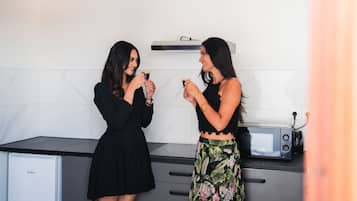 Twee vrouwen in een keuken met een magnetron en een broodrooster op het aanrecht.