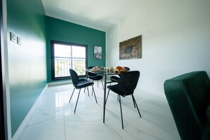 A dining area with a glass table, black chairs, and a green couch. - Takeoff (SAINTE-MARIE)