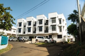 A modern multi-story residential building with a flat roof, multiple balconies, and parked cars in the driveway. - Takeoff (SAINTE-MARIE)