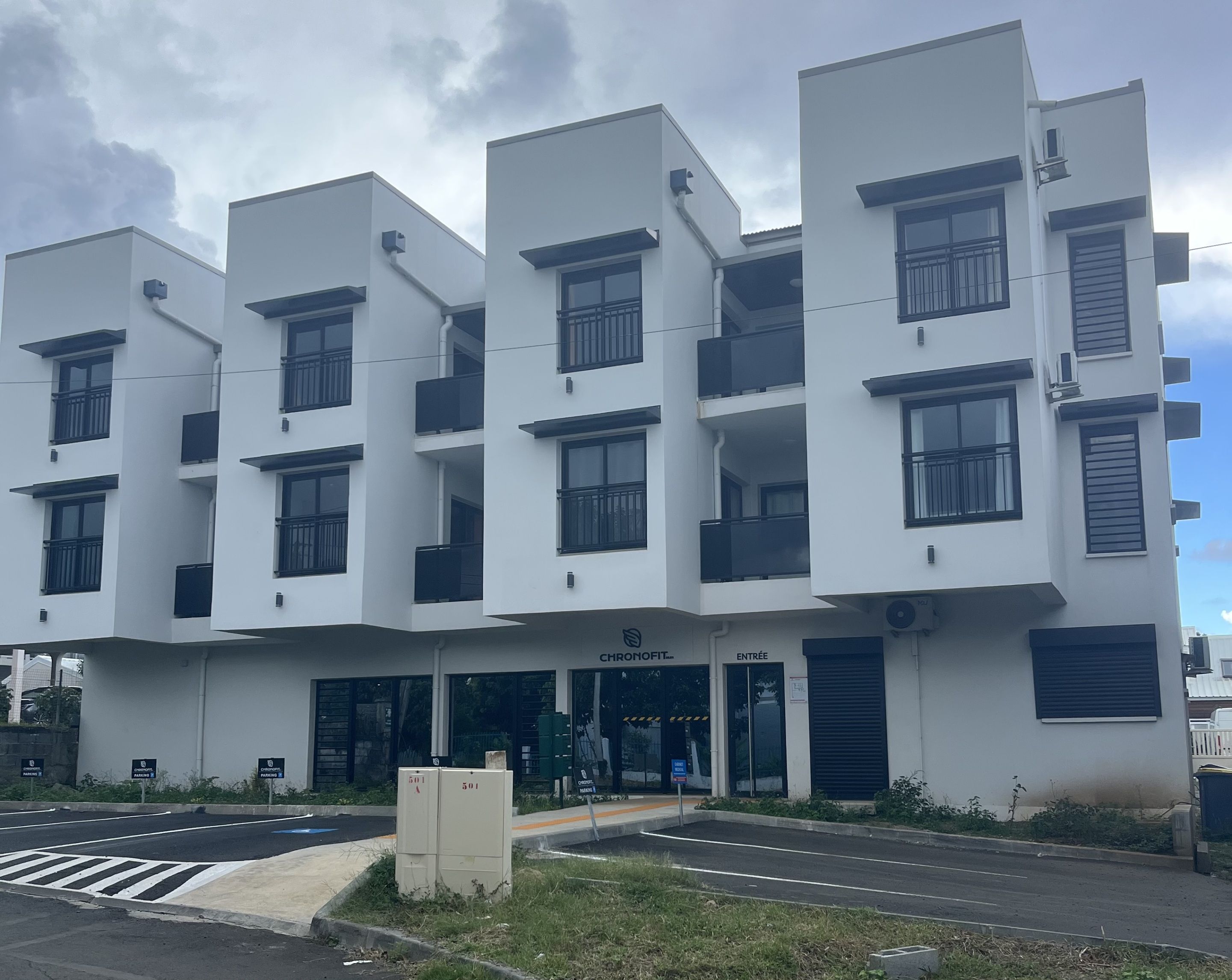 A modern multi-story building with a flat facade, large windows, and balconies.