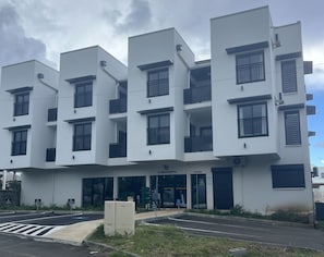 Un edificio moderno de varios pisos con fachada plana, ventanas grandes y balcones.