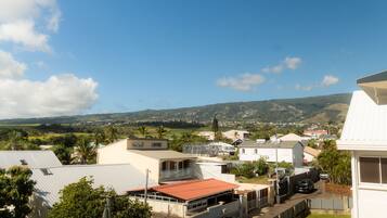 A residential area with houses, a street, and a hilly landscape in the background.