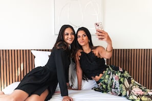 Dos personas sentadas en una cama en una habitación con paneles de madera y una almohada blanca.